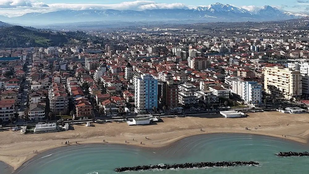 Panorama della città con una spiaggia e montagne sullo sfondo
