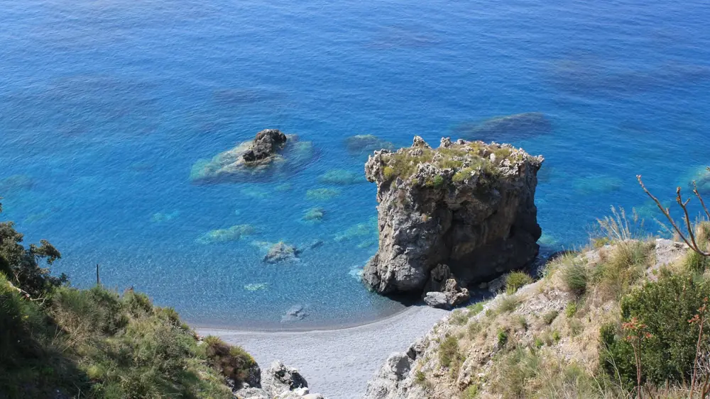 Una spiaggia rocciosa con acqua cristallina e rocce isolate.