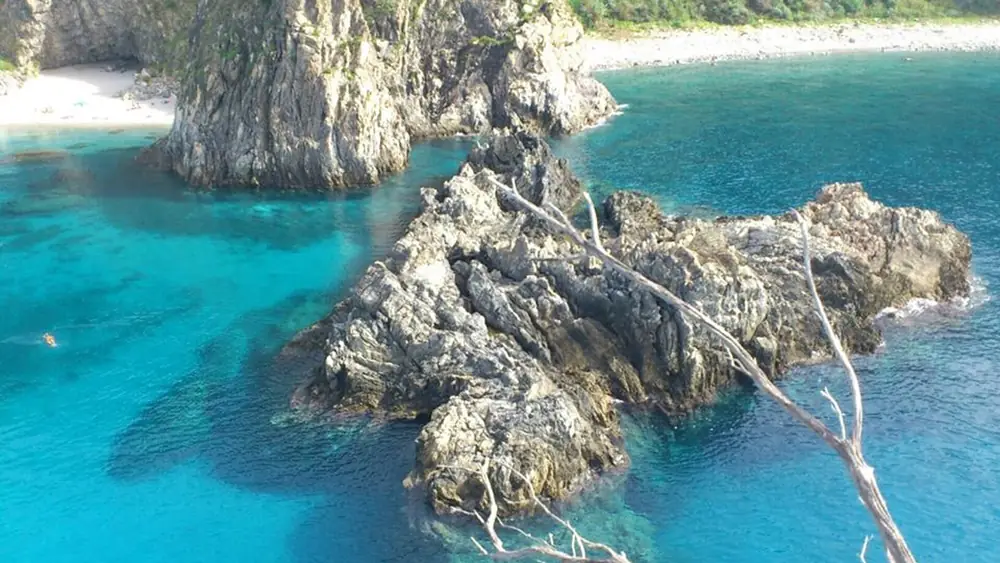 Spiaggia rocciosa con acqua cristallina e cielo blu