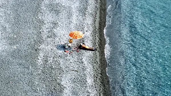 Due persone su una spiaggia con un ombrellone arancione.