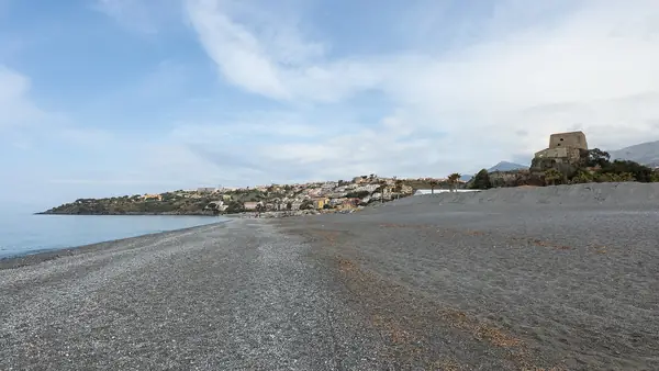 Spiaggia rocciosa con vista sul mare e sulla città sullo sfondo.