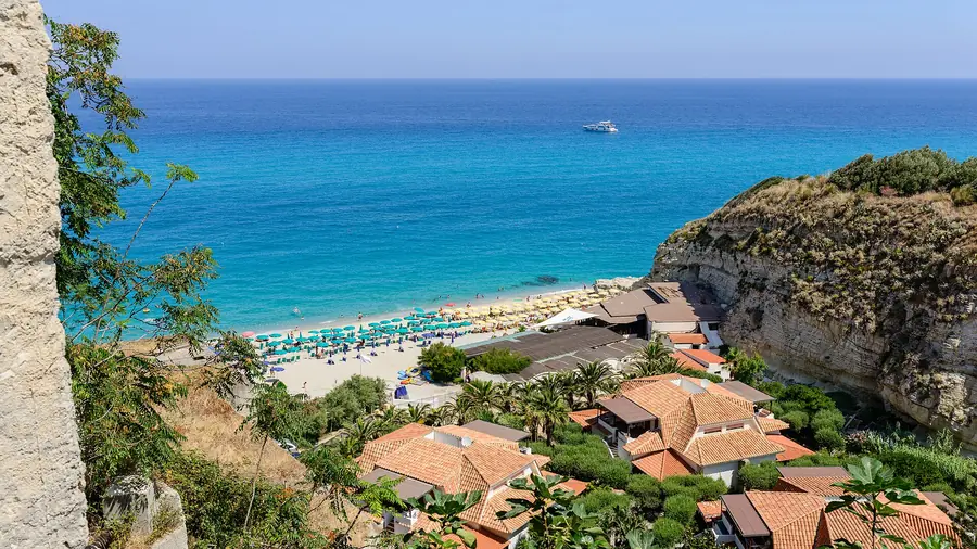 Spiaggia di Tropea con case rosse e mare blu profondo