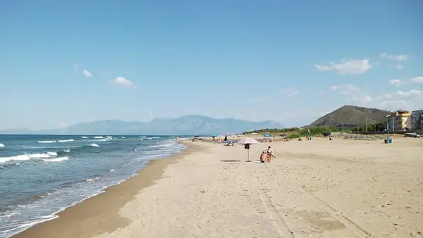 Spiaggia con persone che si rilassano e montagne sullo sfondo