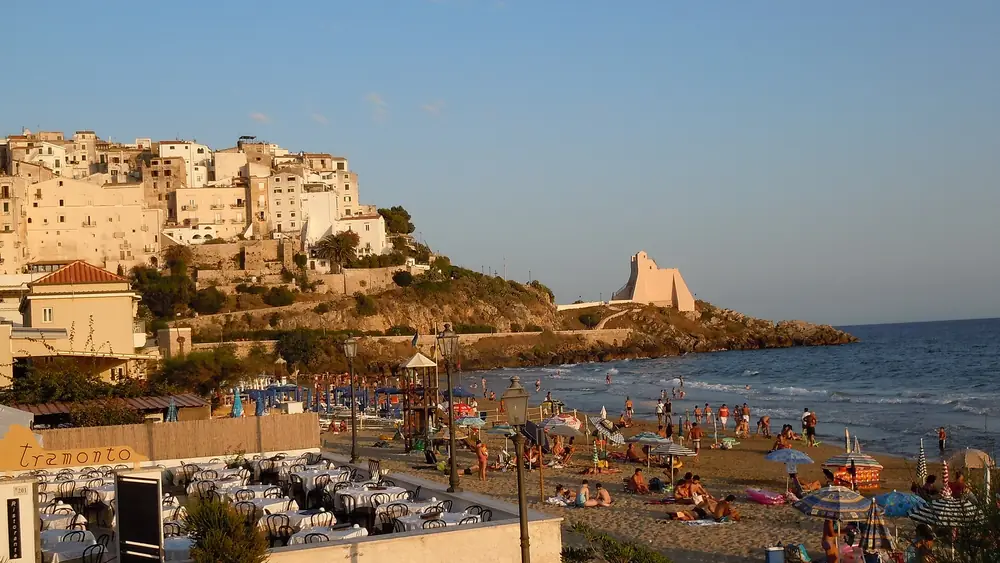 Spiaggia di Sperlonga con persone che si divertono e case sulla collina