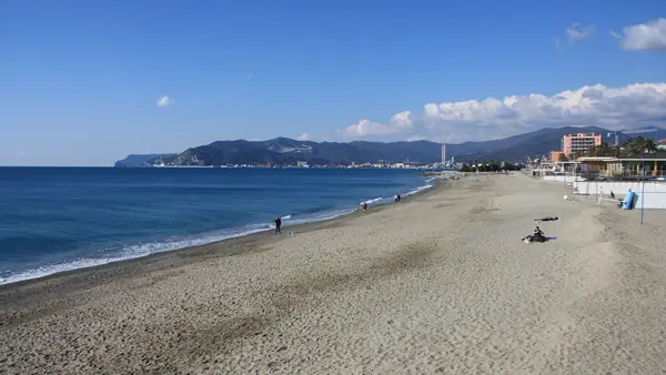 Spiaggia vuota con cielo blu e montagne sullo sfondo.