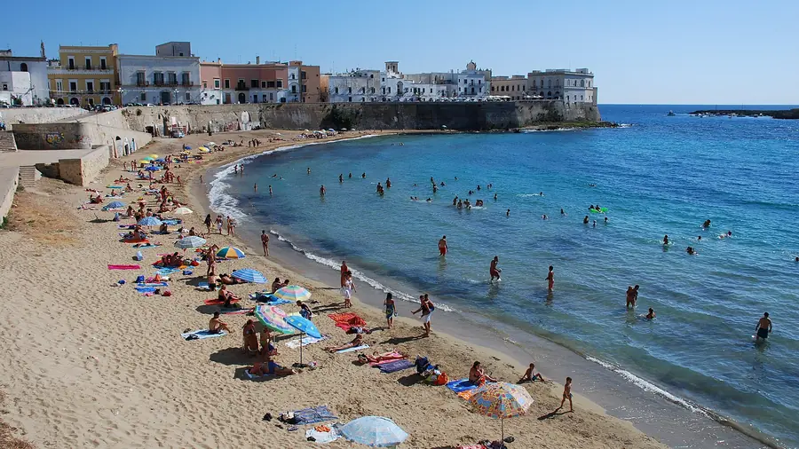 Spiaggia con molti turisti che si divertono in un bel giorno di sole.