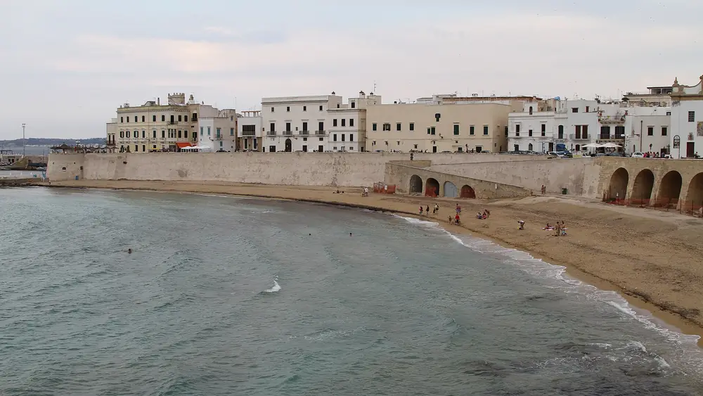 Spiaggia con palazzi storici e persone che si godono il mare