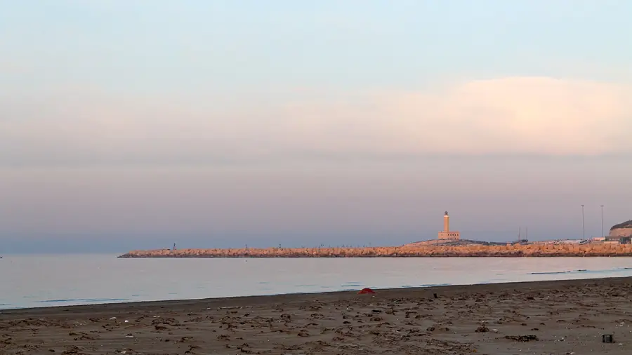 Spiaggia vuota con vista sul faro e sul mare al tramonto