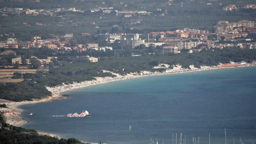Spiaggia di Alghero con case e montagne sullo sfondo