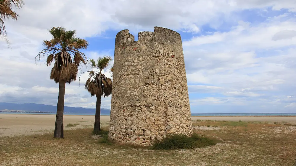 Torre costiera con palme e spiaggia sullo sfondo