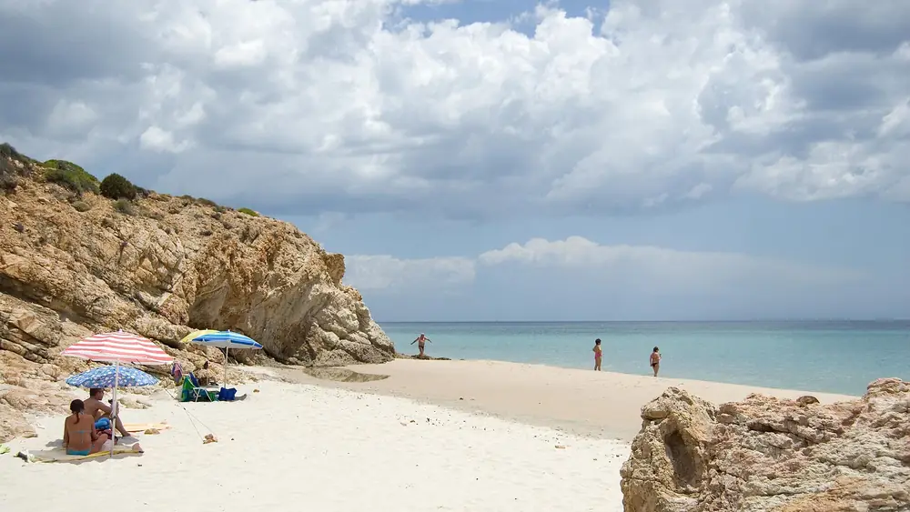 Spiaggia con persone che si godono il mare e rocce intorno