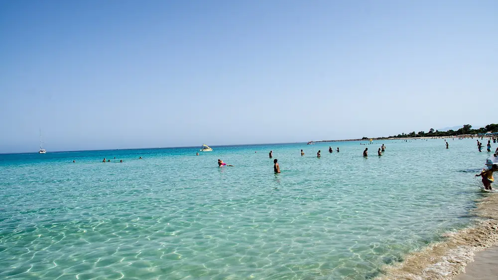 Spiaggia con acqua cristallina e gente che si diverte