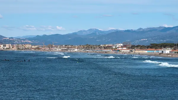Spiaggia con persone che nuotano e montagne sullo sfondo