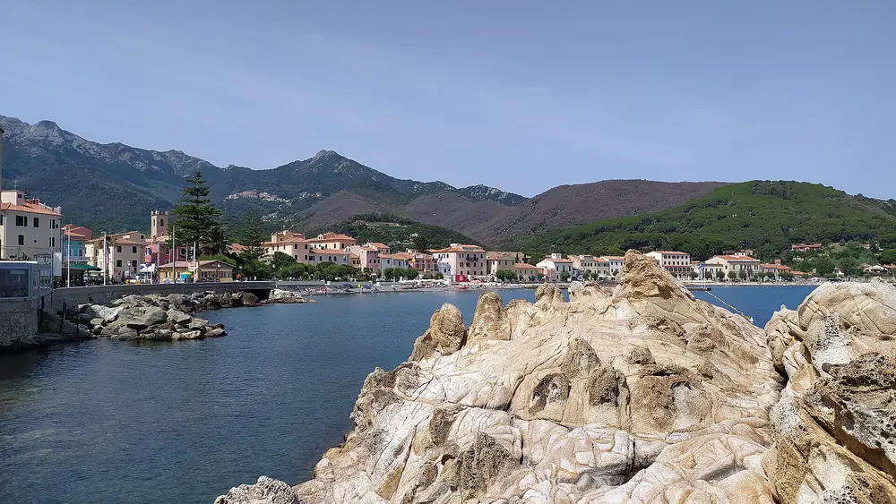 Paesaggio costiero con montagne, case e acqua blu